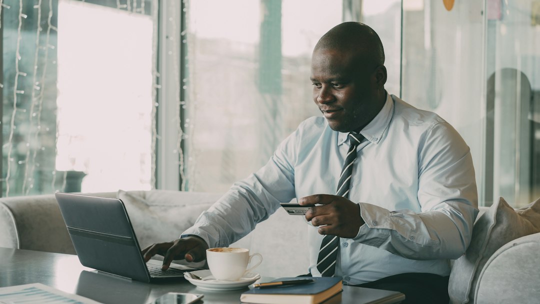 Homme utilisant un ordinateur portable et une carte bancaire